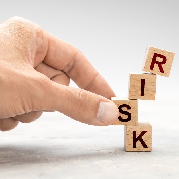 Hand removing 'S' from 'risk' in scrabble letters symbolizing minimal risk in selling passive income printables.