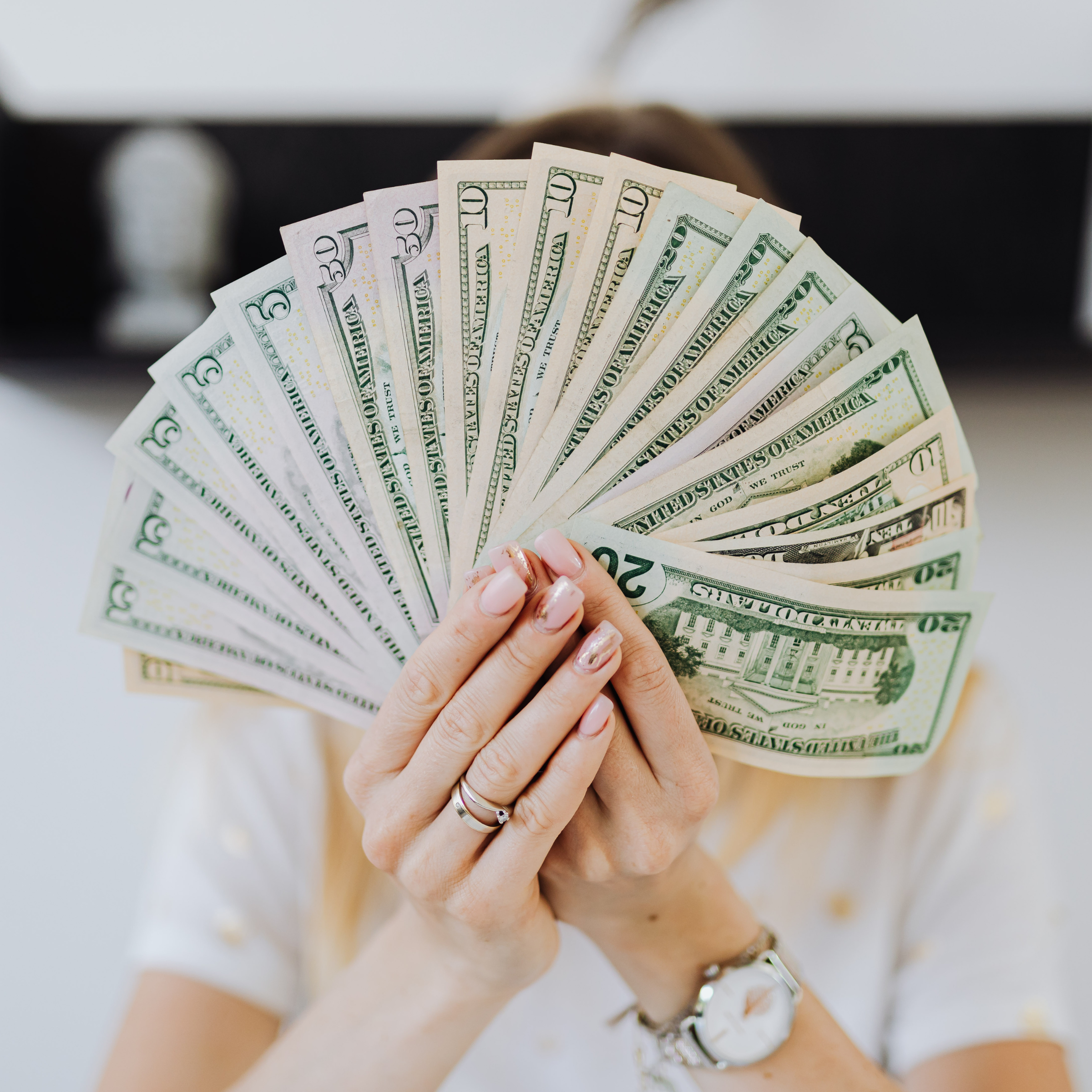 Person holding dollar bills, symbolizing passive income from printables.